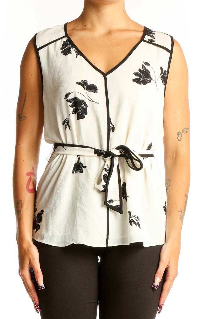 Front view of Vince Camuto white sleeveless blouse with black floral print and tie-waist