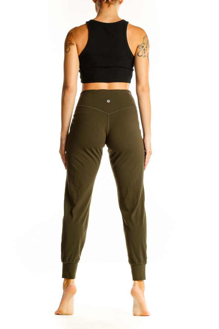 Side view of woman wearing olive green Lululemon jogger pants with black crop top