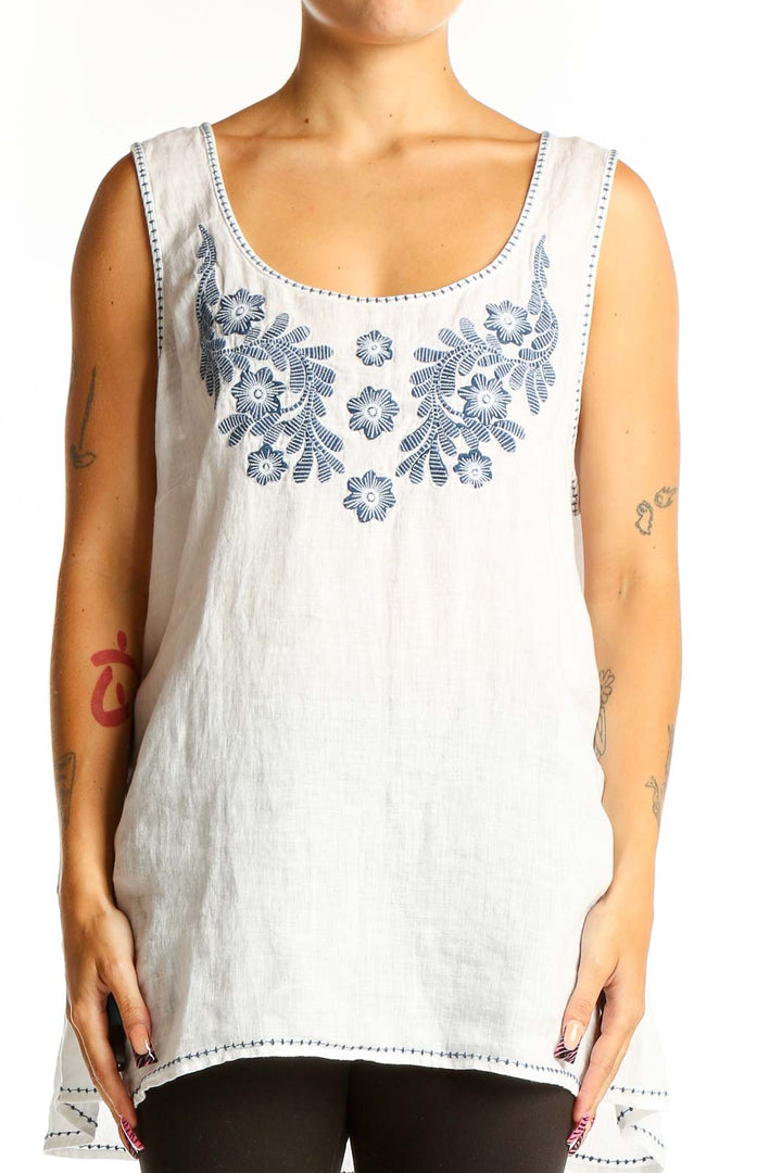 Front view of white linen sleeveless top with blue floral embroidery