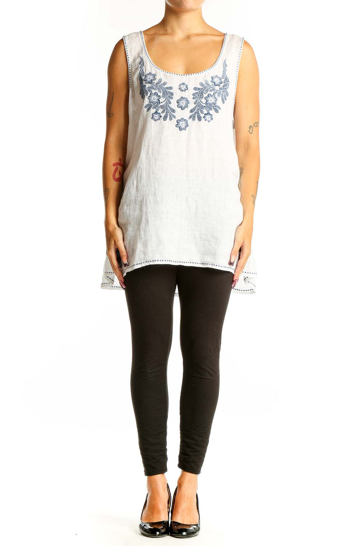 Front view of white linen sleeveless top with blue floral embroidery
