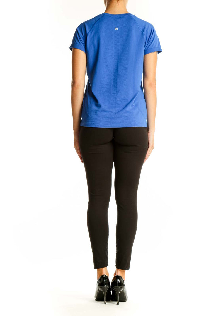 Side view of woman wearing blue Lululemon athletic t-shirt with black pants