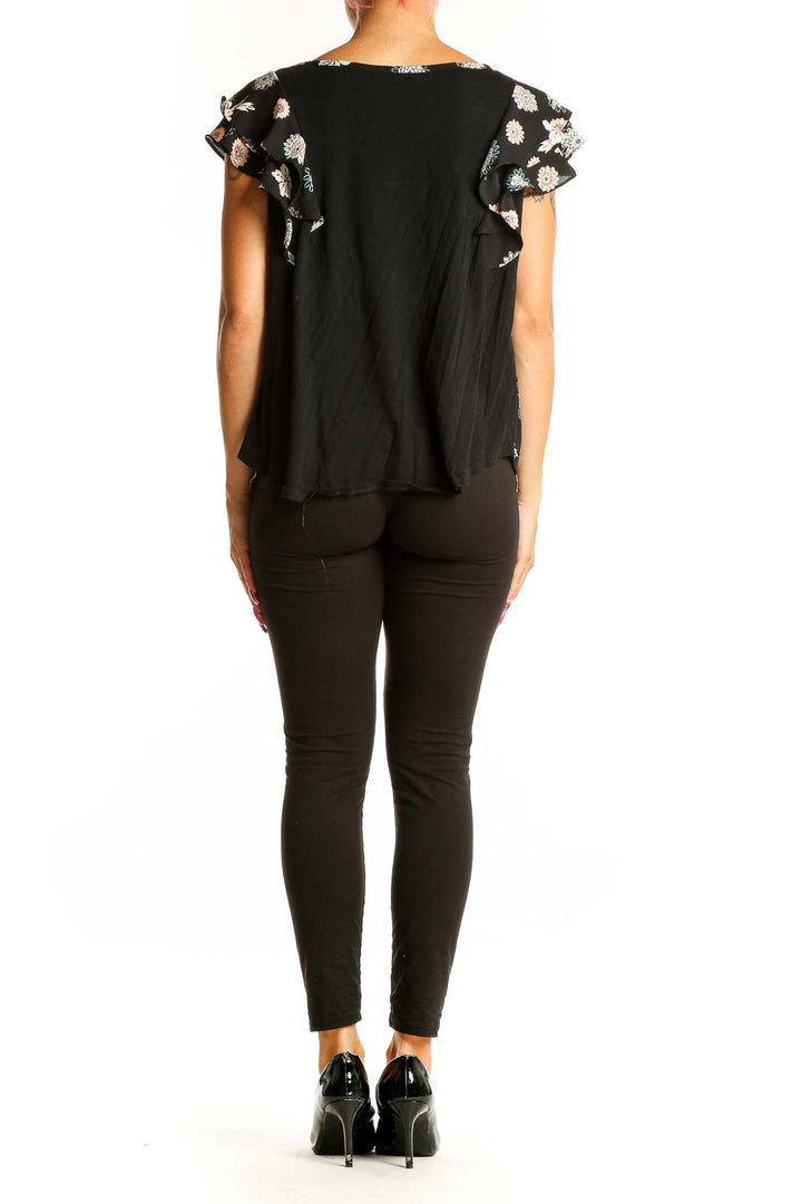 Side view of woman wearing LOFT Outlet black floral print top with black pants