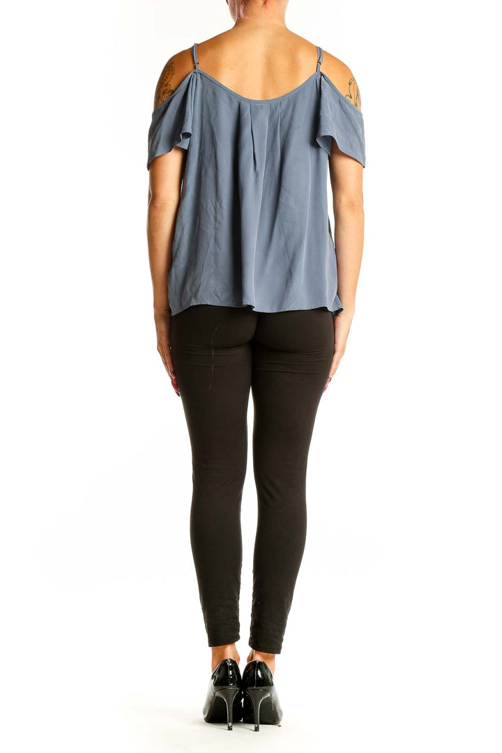 Side view of model wearing Joie blue silk cold-shoulder camisole top with black pants