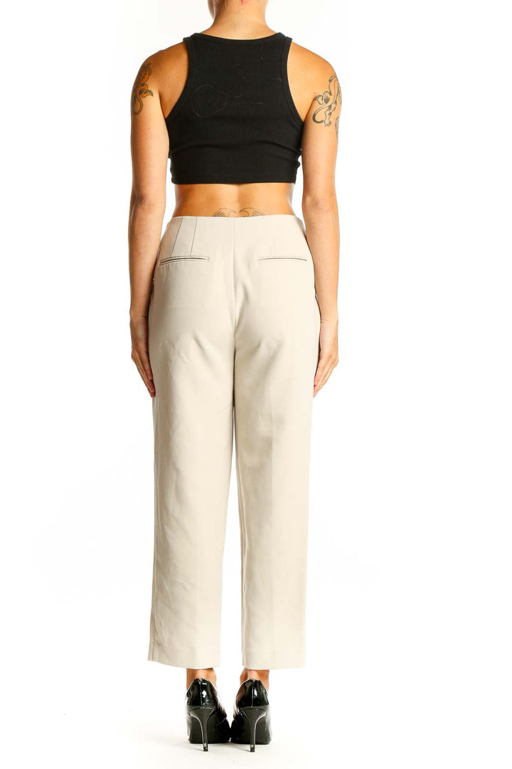 Side view of model wearing Ann Taylor beige tailored ankle-length trousers with black top