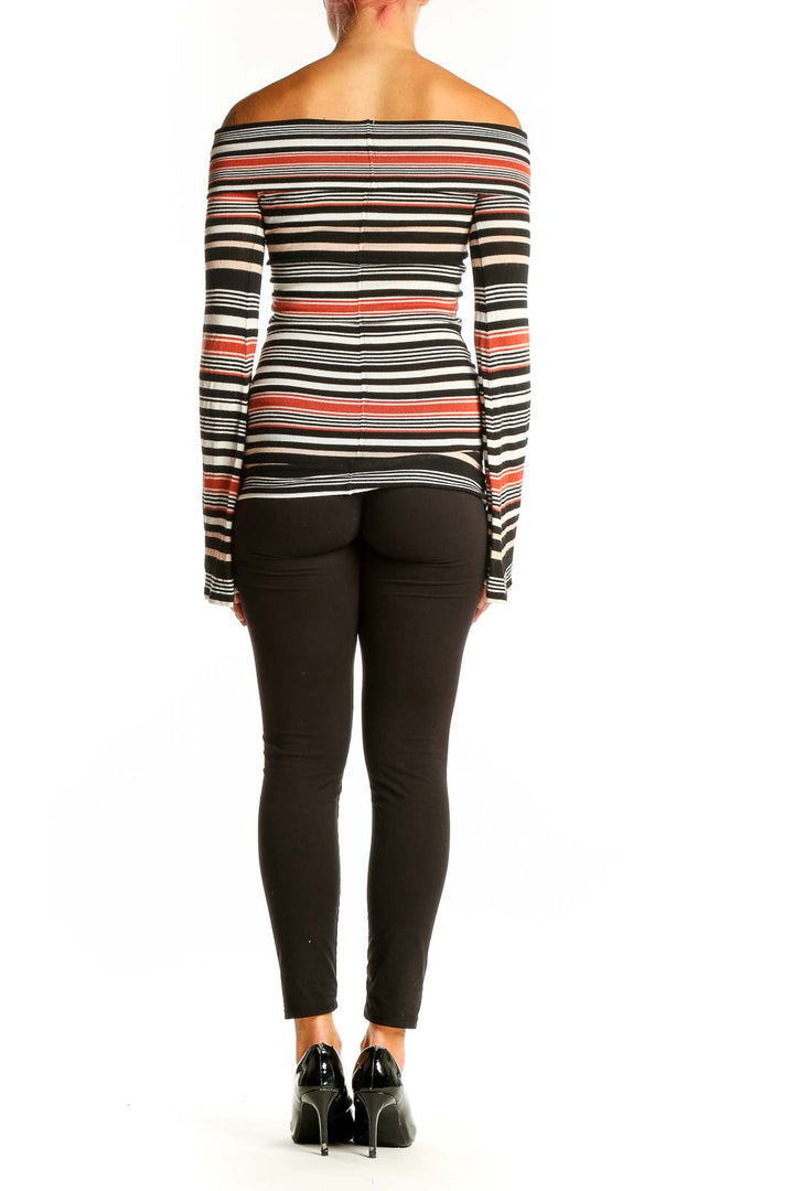 Side view of model wearing Free People Black Striped Off-Shoulder Knit Top with black pants