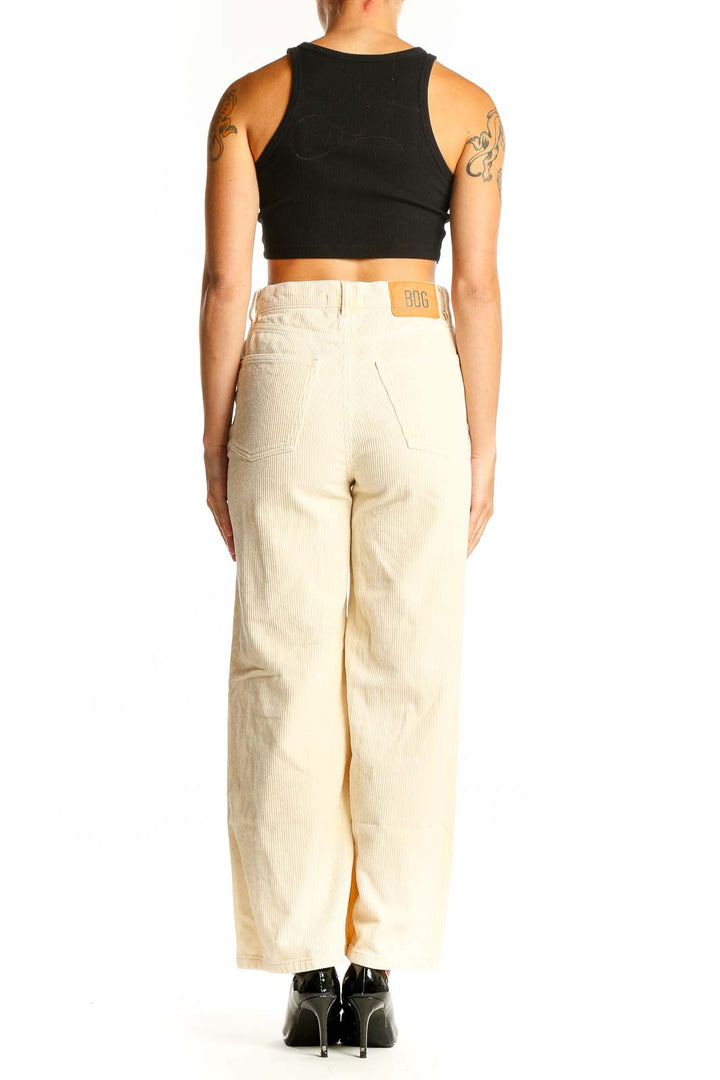 Side view of woman wearing BDG cream corduroy wide-leg pants with black top