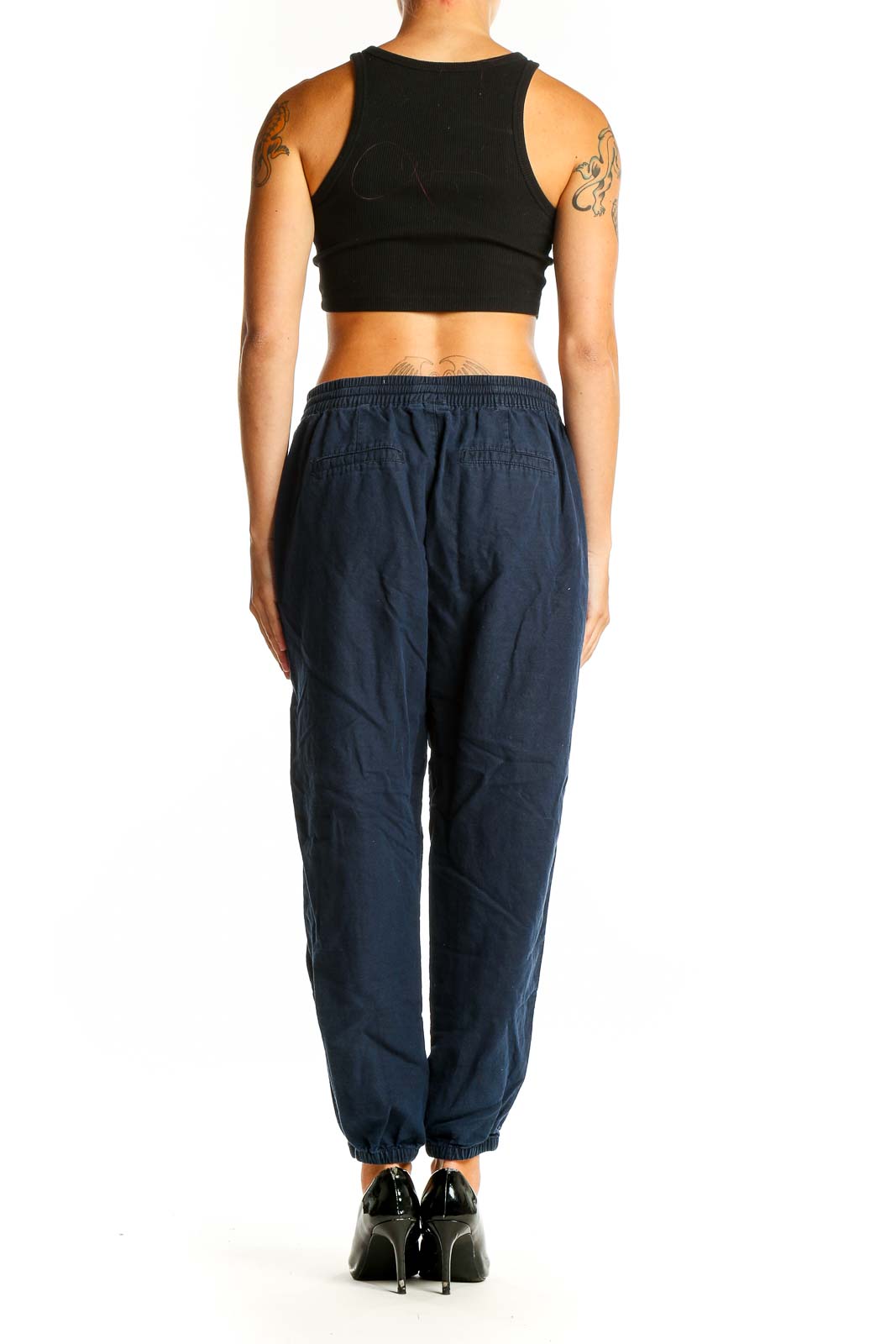Side view of woman wearing navy Gap jogger pants with black crop top