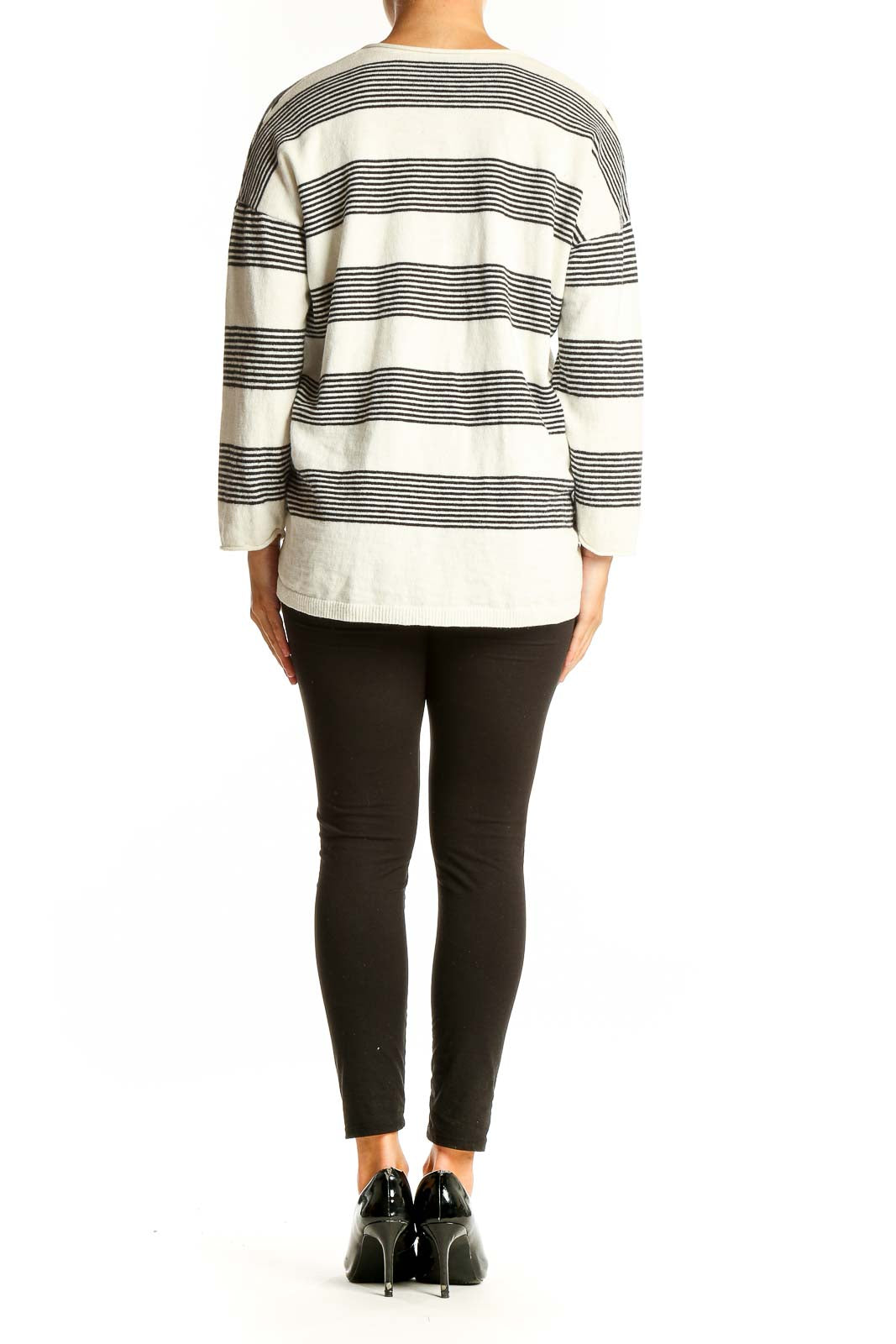 Side view of model wearing Madewell white and black striped V-neck sweater with black pants