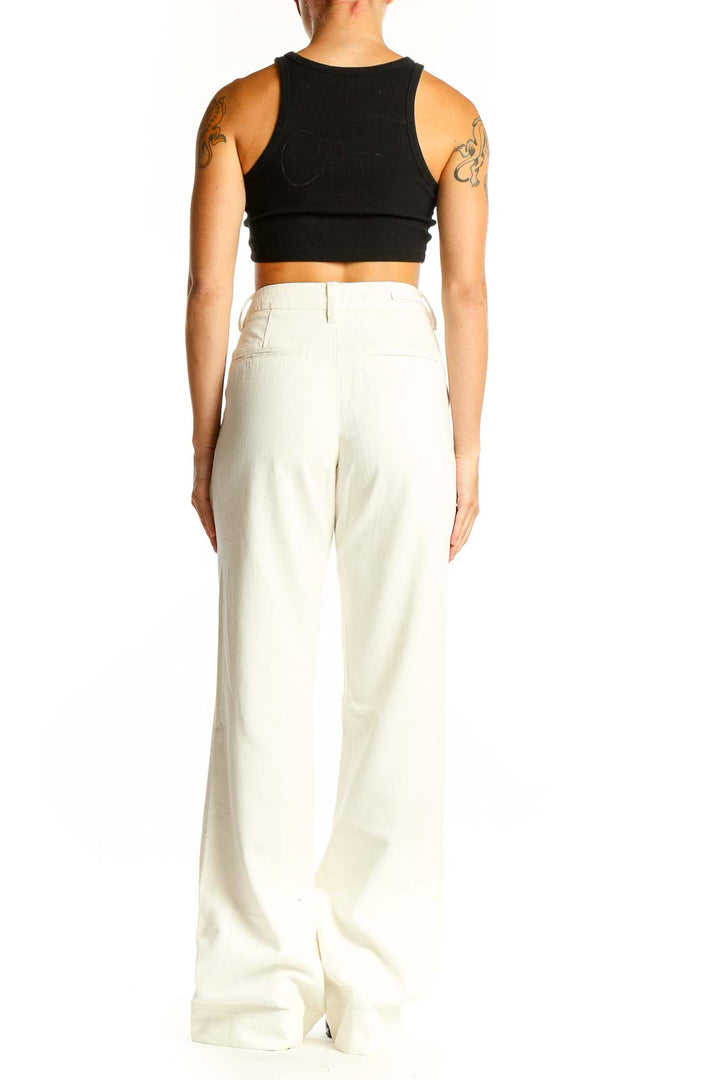 Side view of model wearing Paige white wide-leg trousers with black crop top