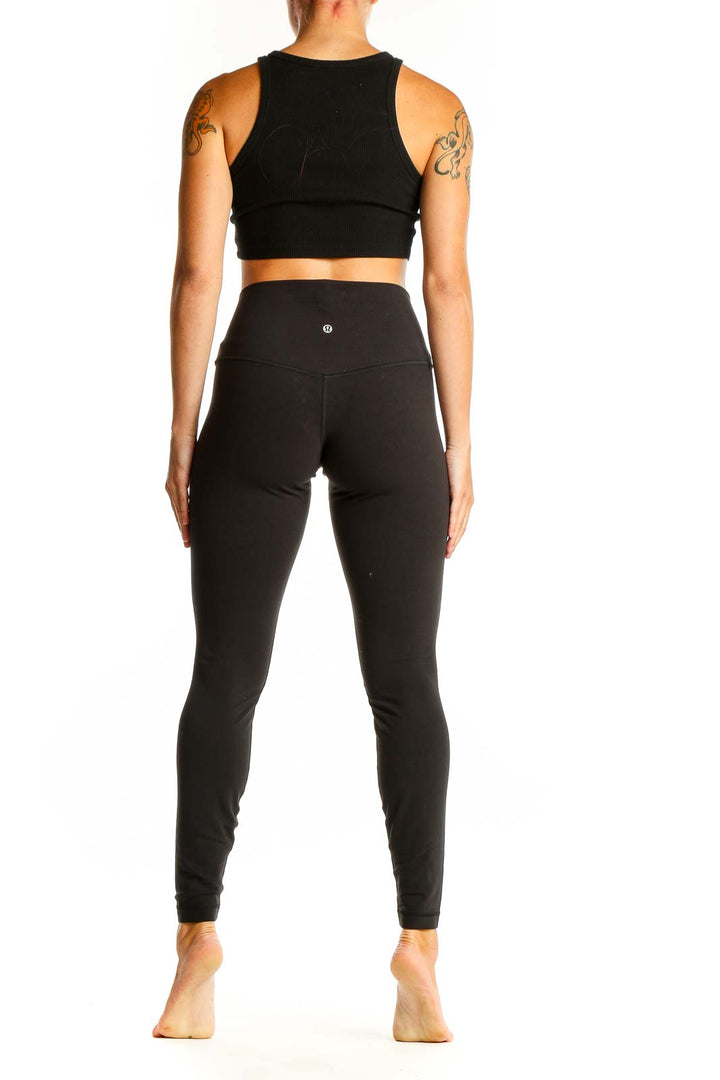 Side view of woman wearing black Lululemon high-waisted leggings and matching crop top
