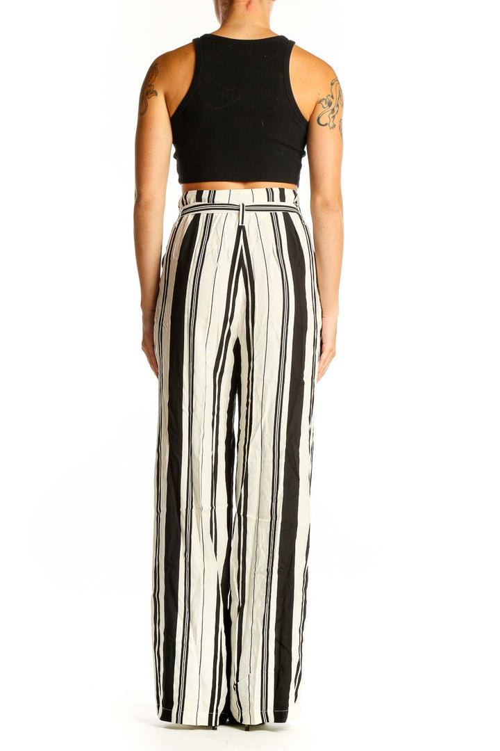 Side view of model wearing Chelsea 28 black and white striped wide-leg pants with black crop top