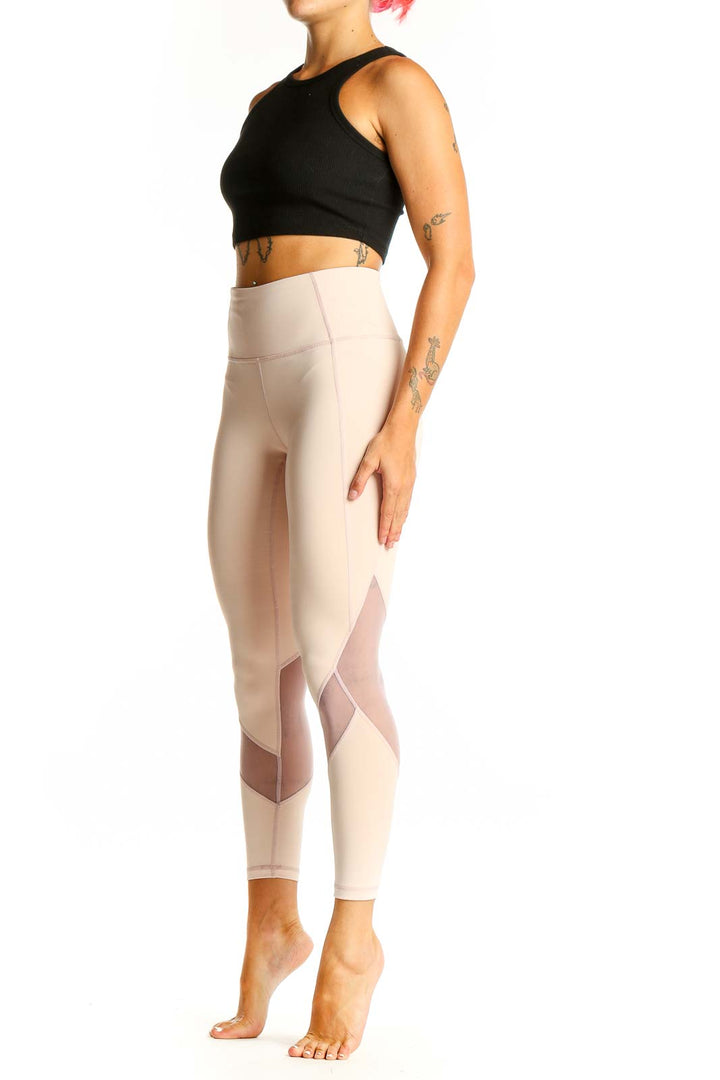 Front view of beige Athleta high-waisted leggings with mesh panels