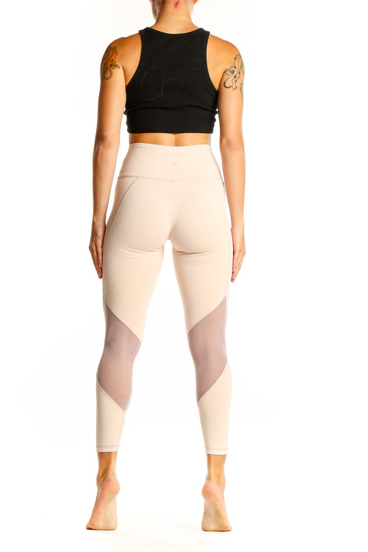 Side view of woman wearing beige Athleta high-waisted leggings with black crop top