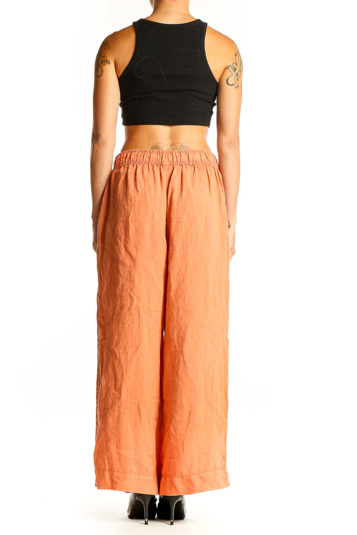 Side view of model wearing Tahari orange linen wide-leg pants with black top