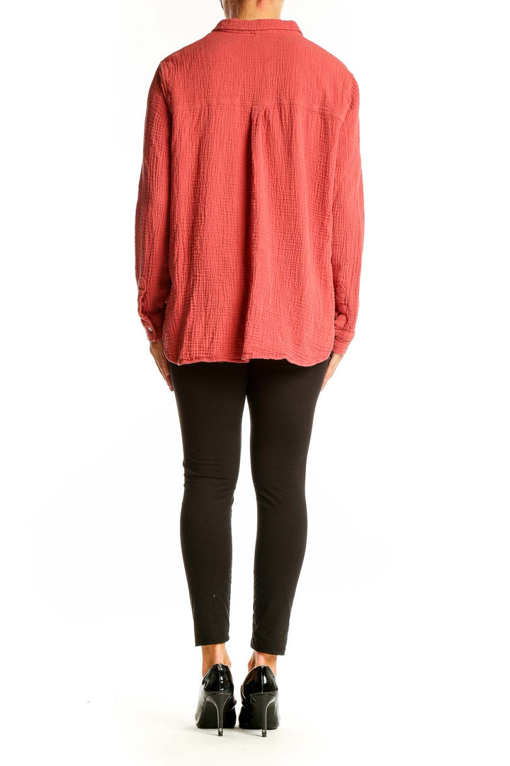 Side view of model wearing Jessica Simpson coral textured button-down shirt with black pants