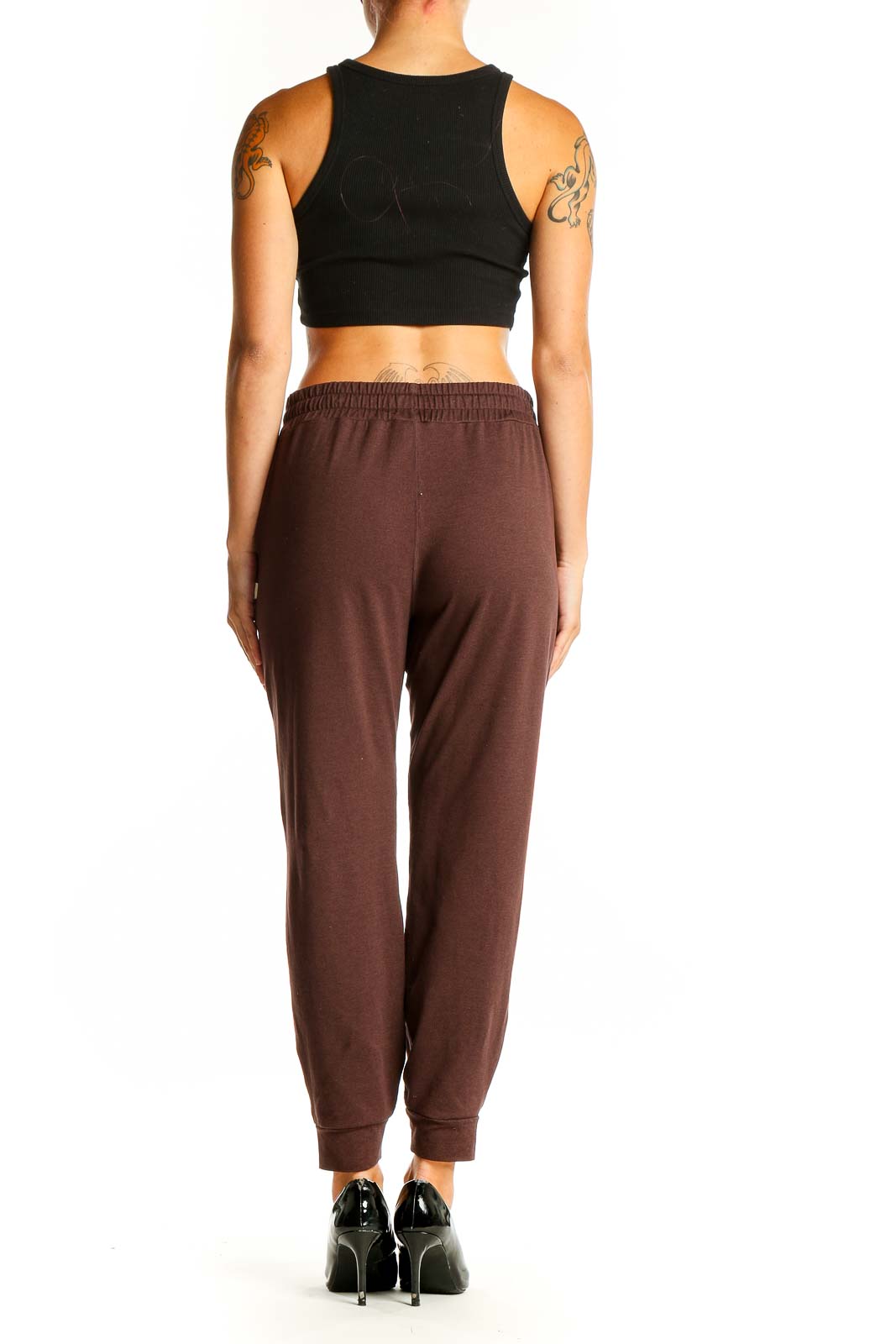 Side view of woman wearing brown Vuori jogger pants with black crop top
