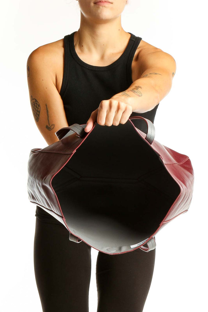 Side view of burgundy leather tote bag worn on shoulder