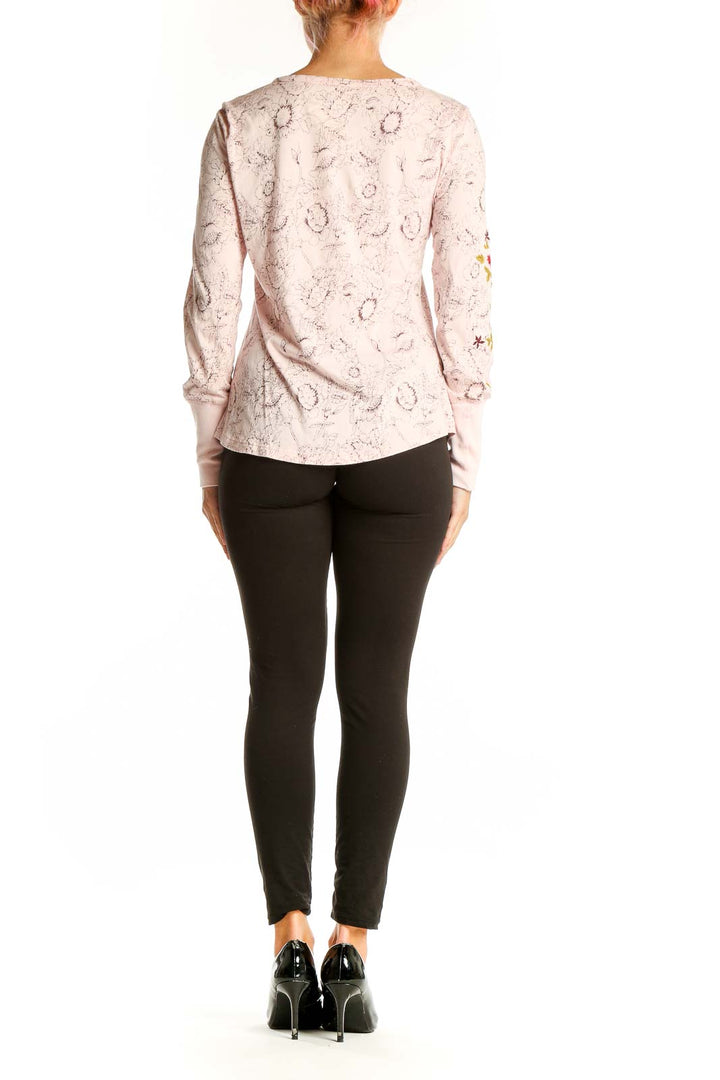 Side view of woman wearing pink Sundance embroidered long sleeve top with black pants