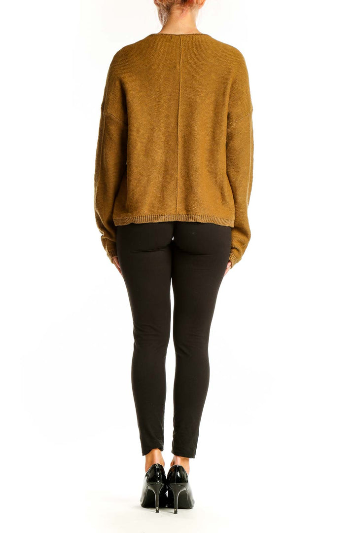Side view of model wearing Sanctuary mustard V-neck cotton knit sweater with black pants