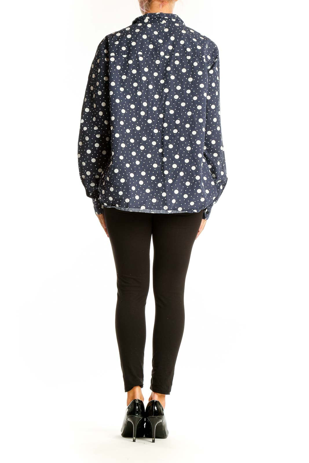 Side view of woman wearing Boden navy polka dot cotton button-up shirt with black pants