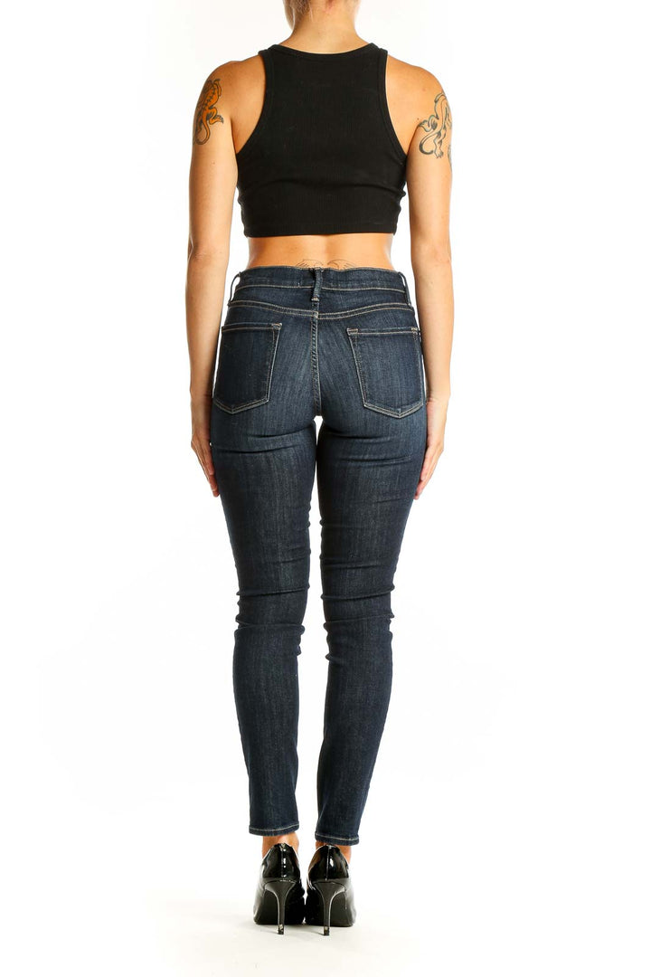 Back view of dark blue FRAME Denim skinny jeans on model