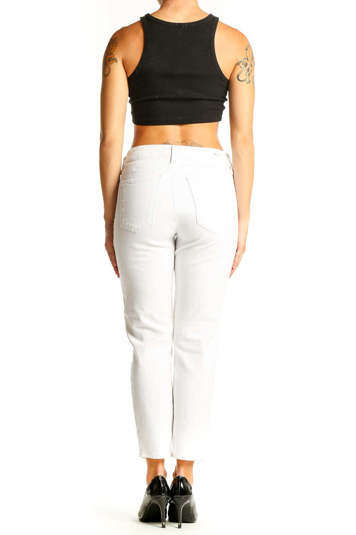 Side view of model wearing white ankle-length jeans with black crop top