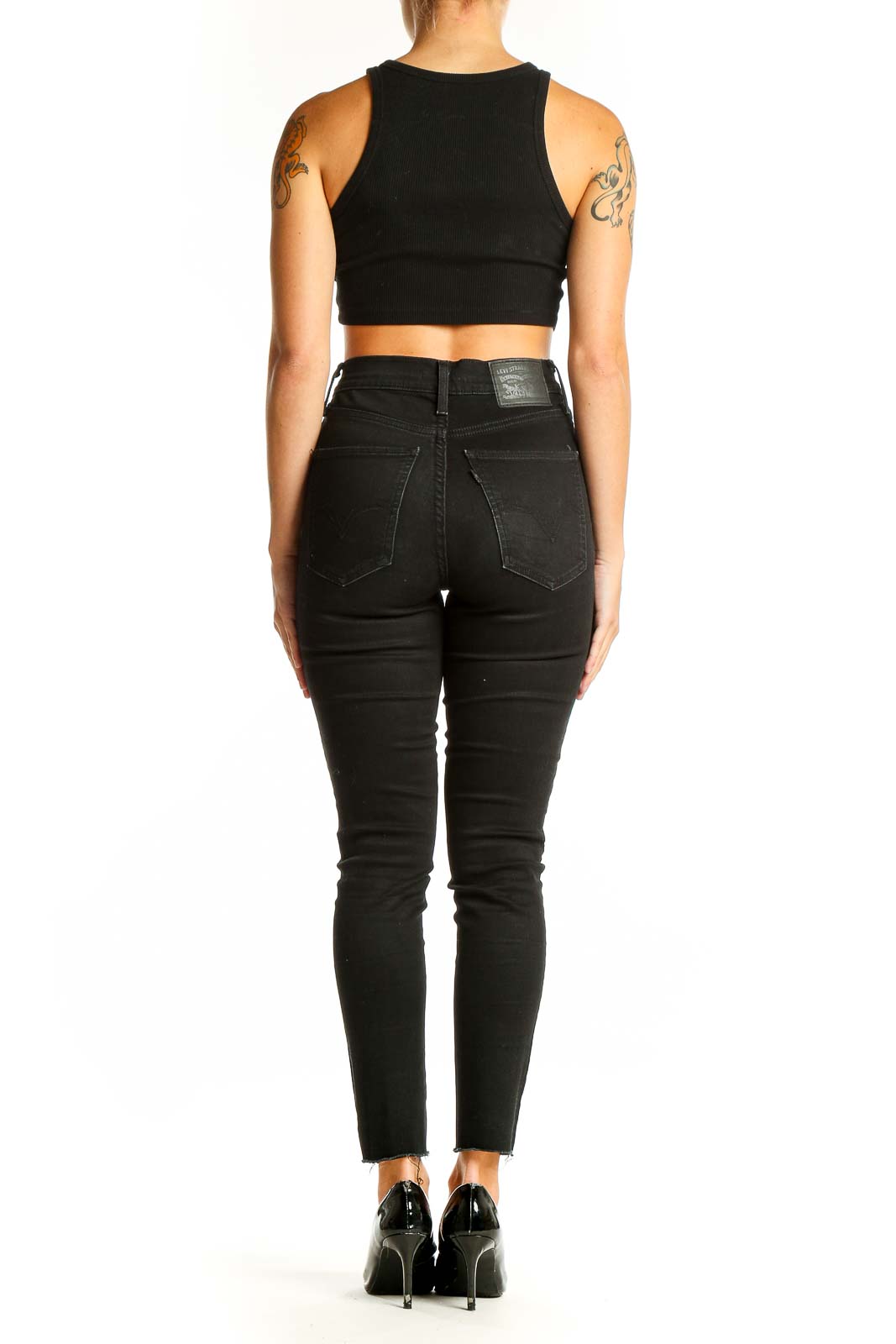Side view of woman wearing Levi's black high-waisted skinny jeans with crop top