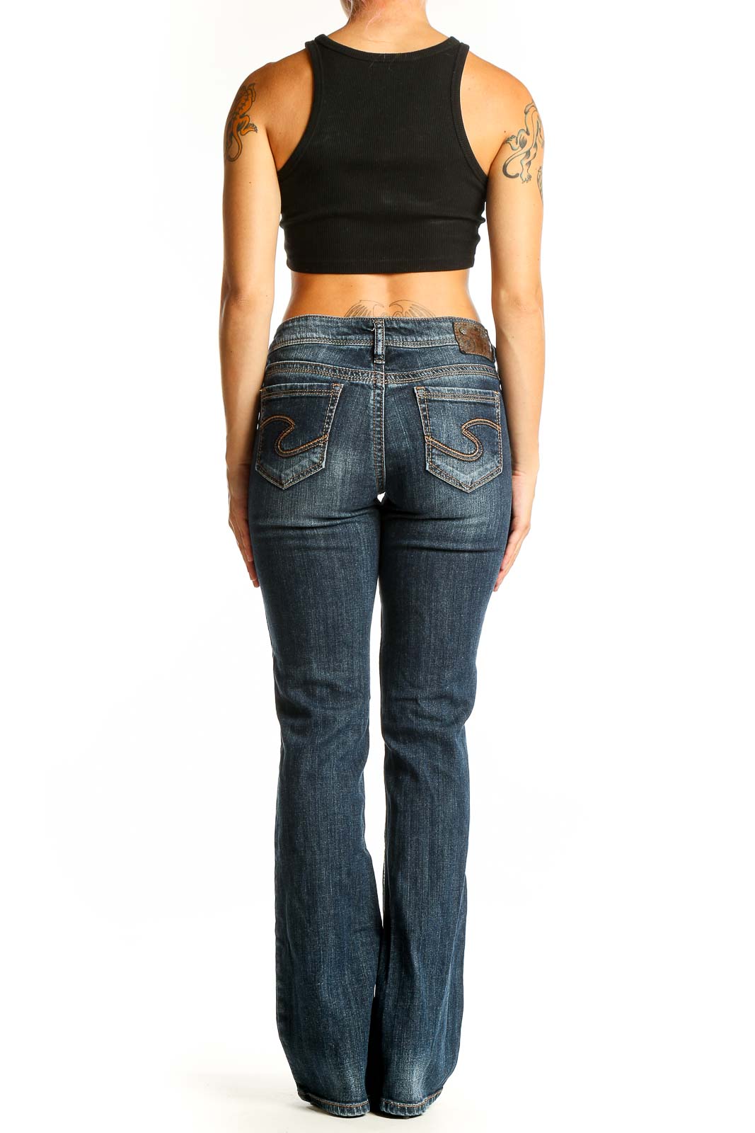 Side view of Silver Jeans Co. dark blue bootcut jeans on model with black crop top