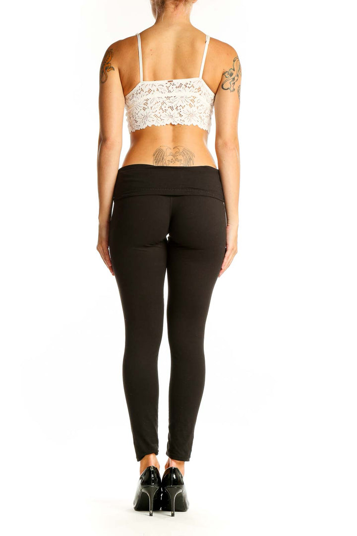 Side view of model wearing white lace crop top bralette with black pants