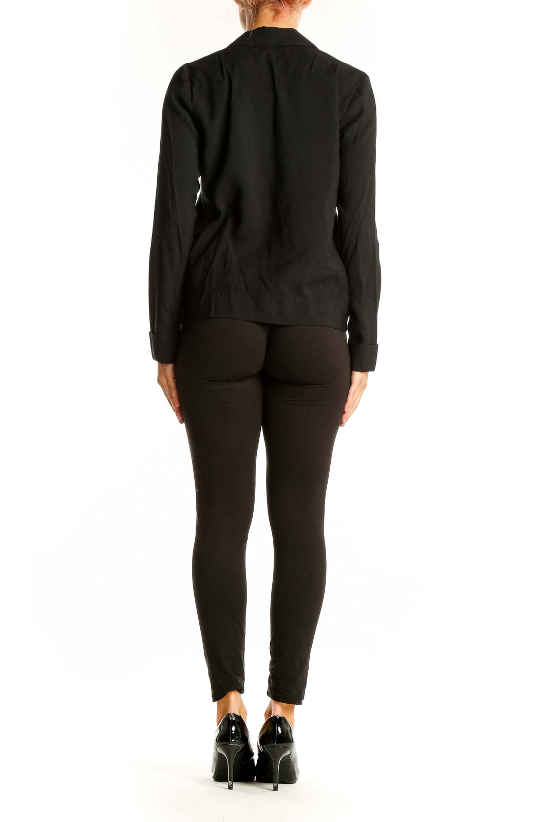 Side view of model wearing black Calvin Klein button-up blouse with black pants
