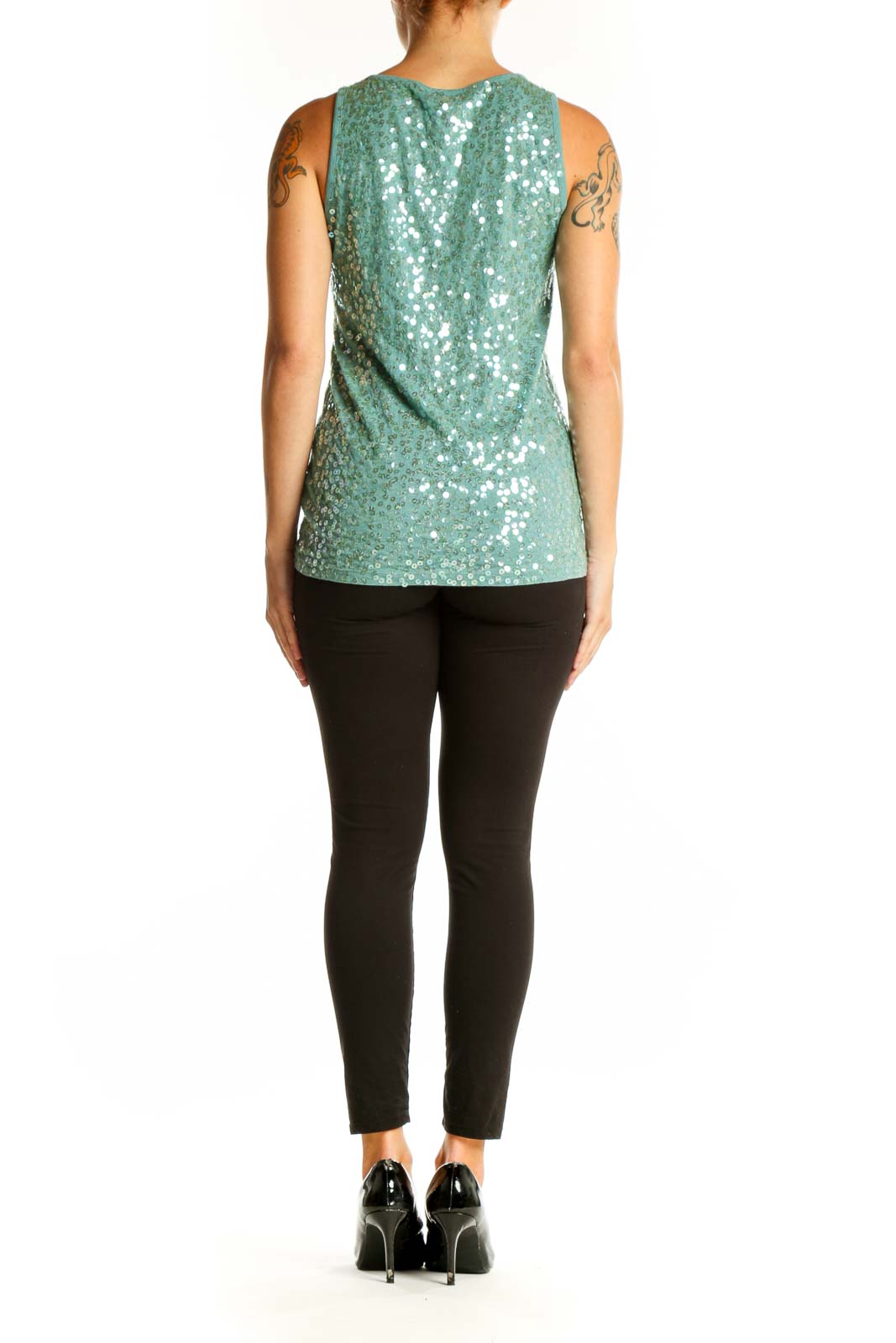 Side view of model wearing DKNY mint green sequined tank top with black pants