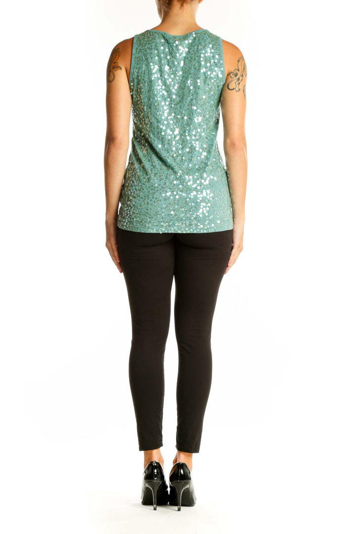 Side view of model wearing DKNY mint green sequined tank top with black pants