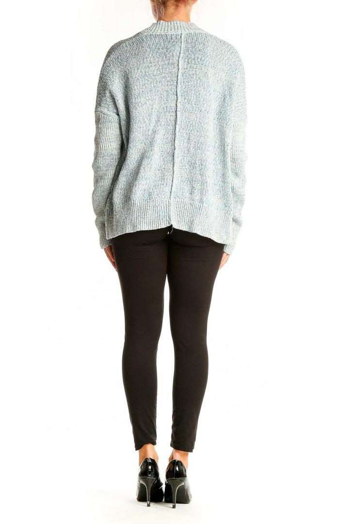 Side view of light blue Gap open front knit cardigan styled with black top and pants
