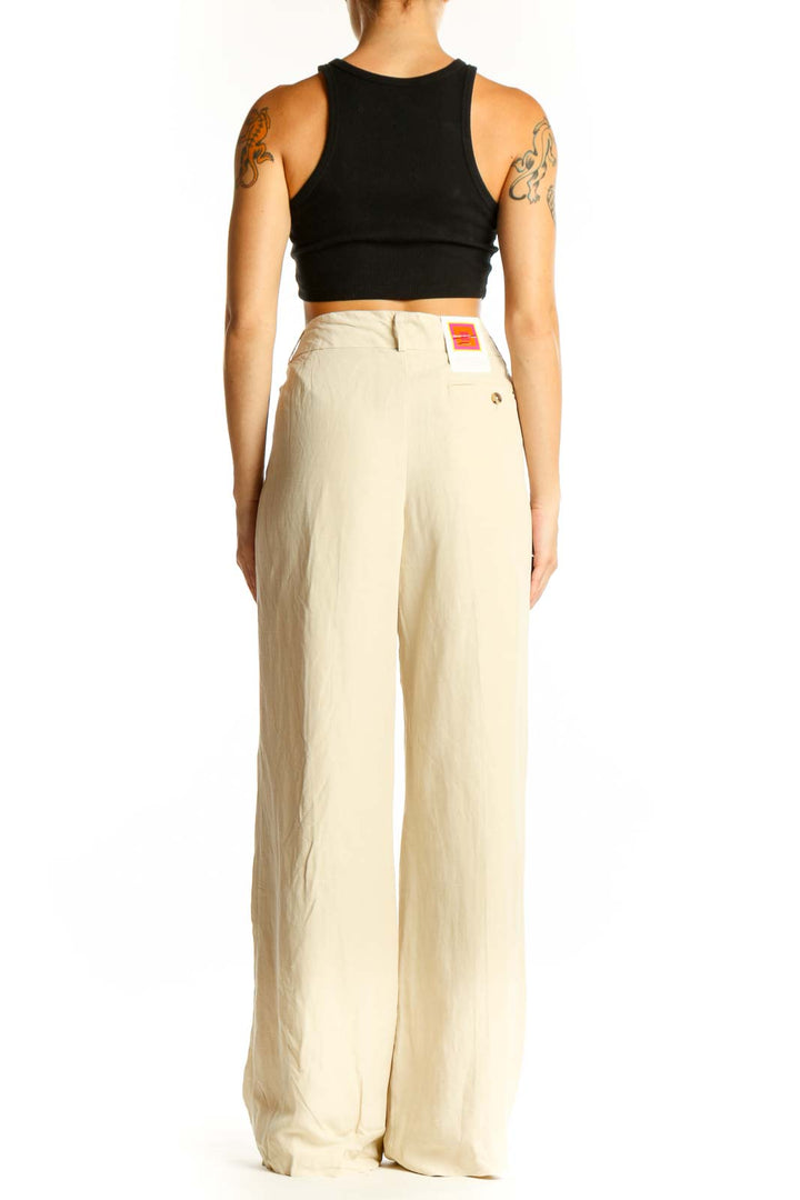 Side view of model wearing Isaac Mizrahi beige wide-leg pants with black crop top