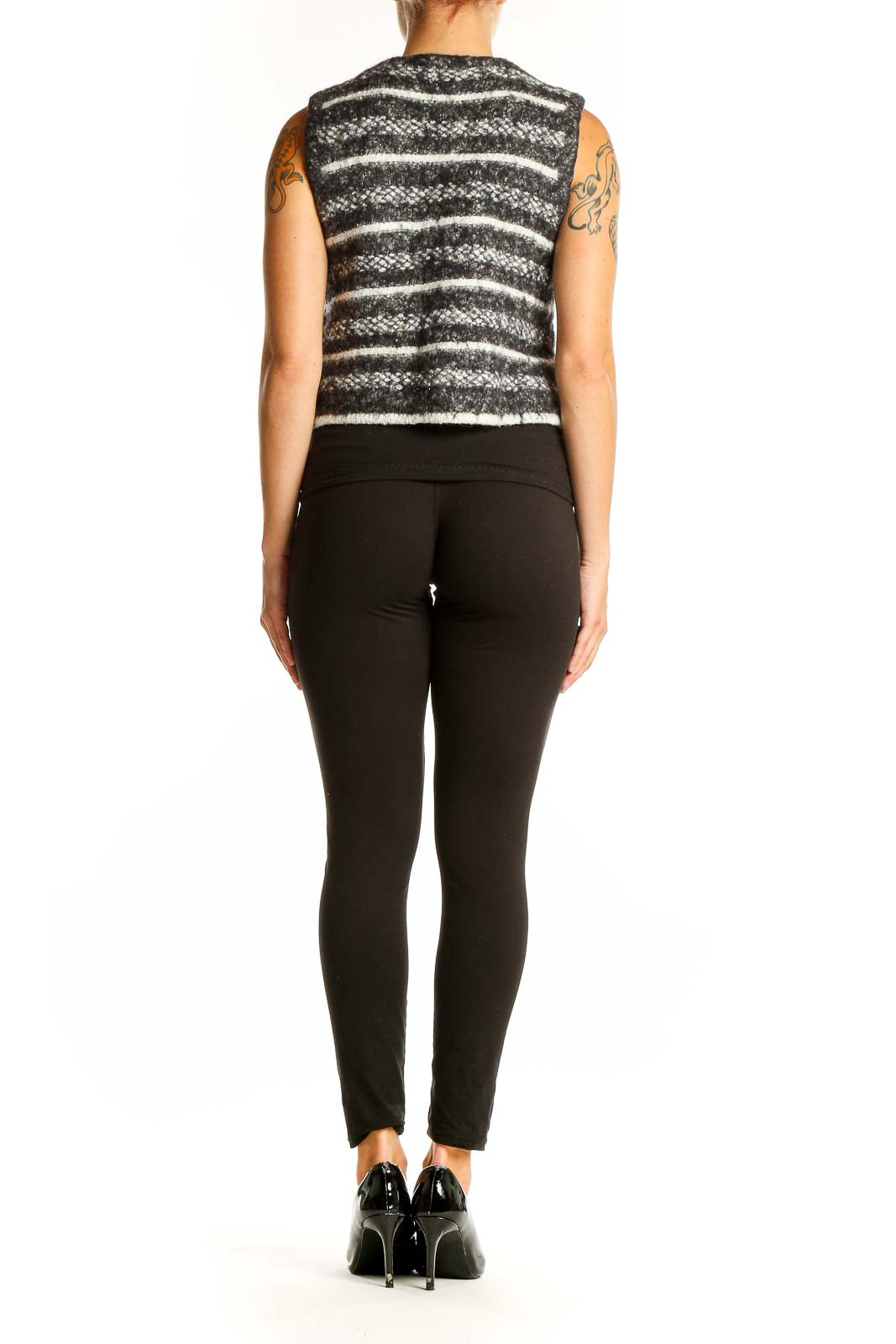 Side view of model wearing gray striped cropped knit vest with black pants