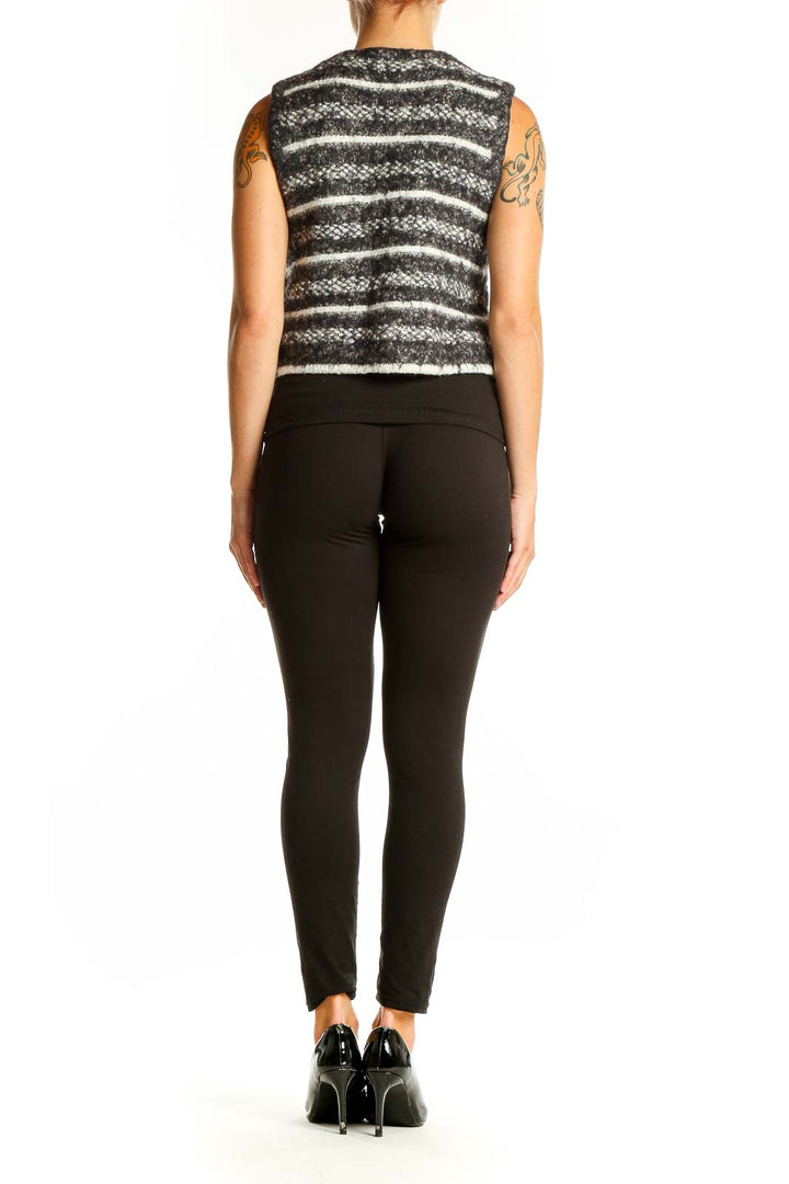 Side view of model wearing gray striped cropped knit vest with black pants