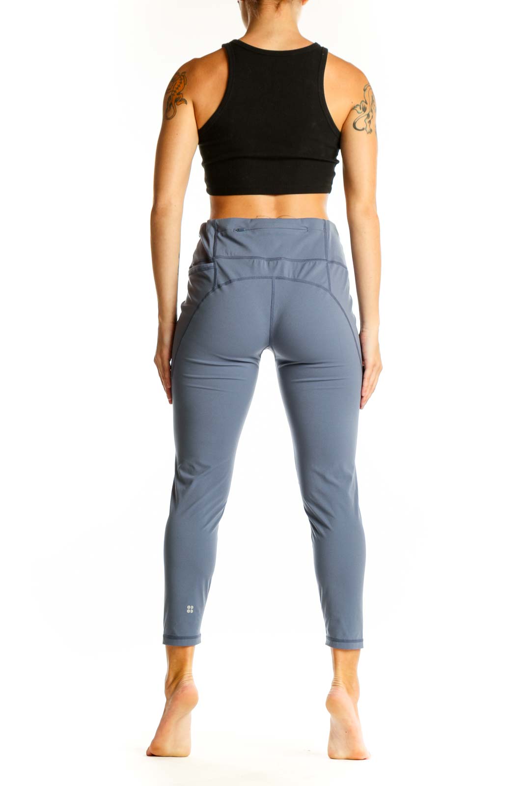 Side view of woman wearing Sweaty Betty blue high-waisted performance leggings and black crop top