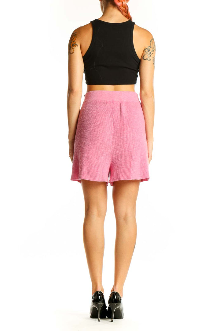 Side view of woman wearing pink FP Beach shorts with black crop top