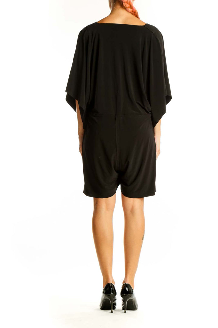 Side view of black NORMA KAMALI mini dress showing flowy silhouette