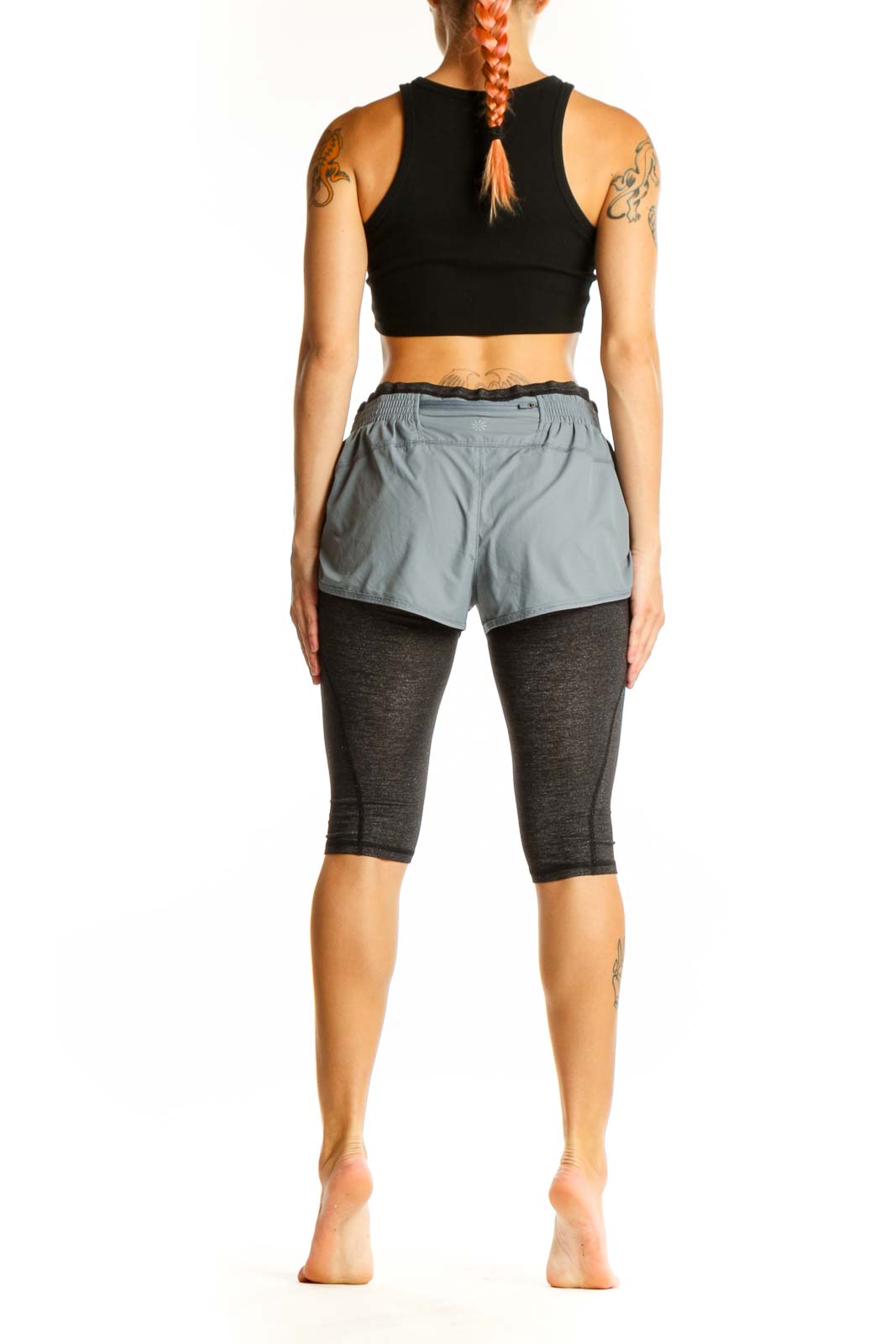 Side view of woman wearing gray Athleta layered athletic shorts with black crop top