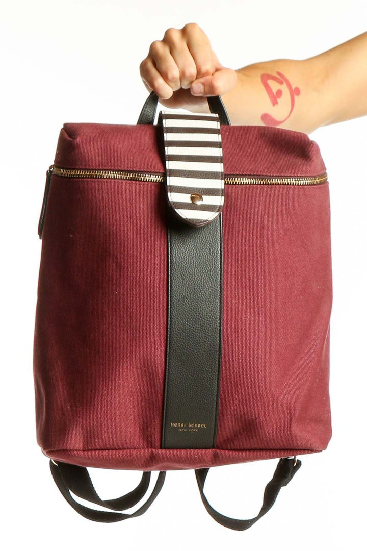 Front view of burgundy Henry Bendel canvas backpack with striped handle