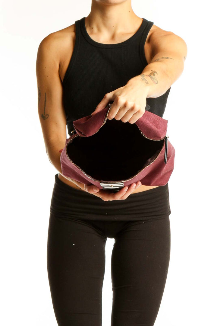 Side view of burgundy Henry Bendel canvas backpack worn by model