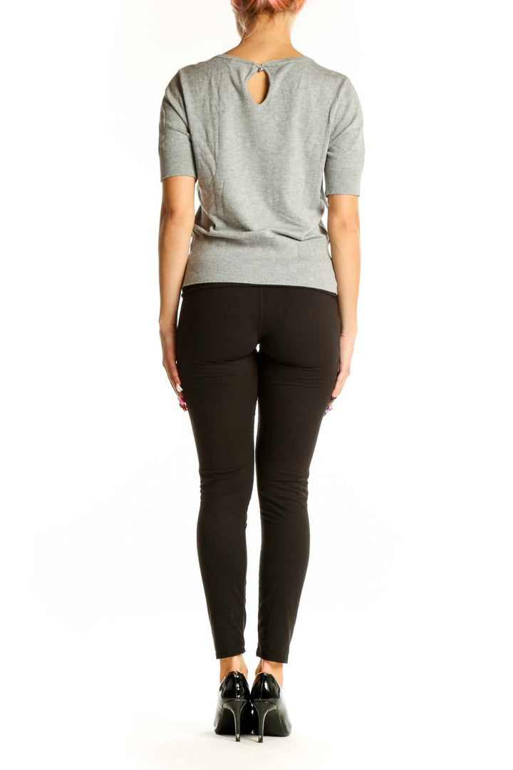 Side view of woman wearing gray short-sleeve knit top with black pants