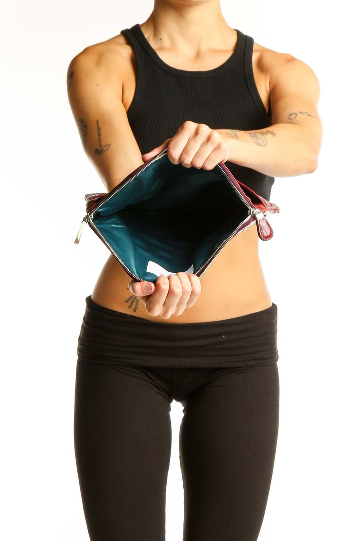 Model holding burgundy Henri Bendel croc-embossed clutch, showcasing size and style