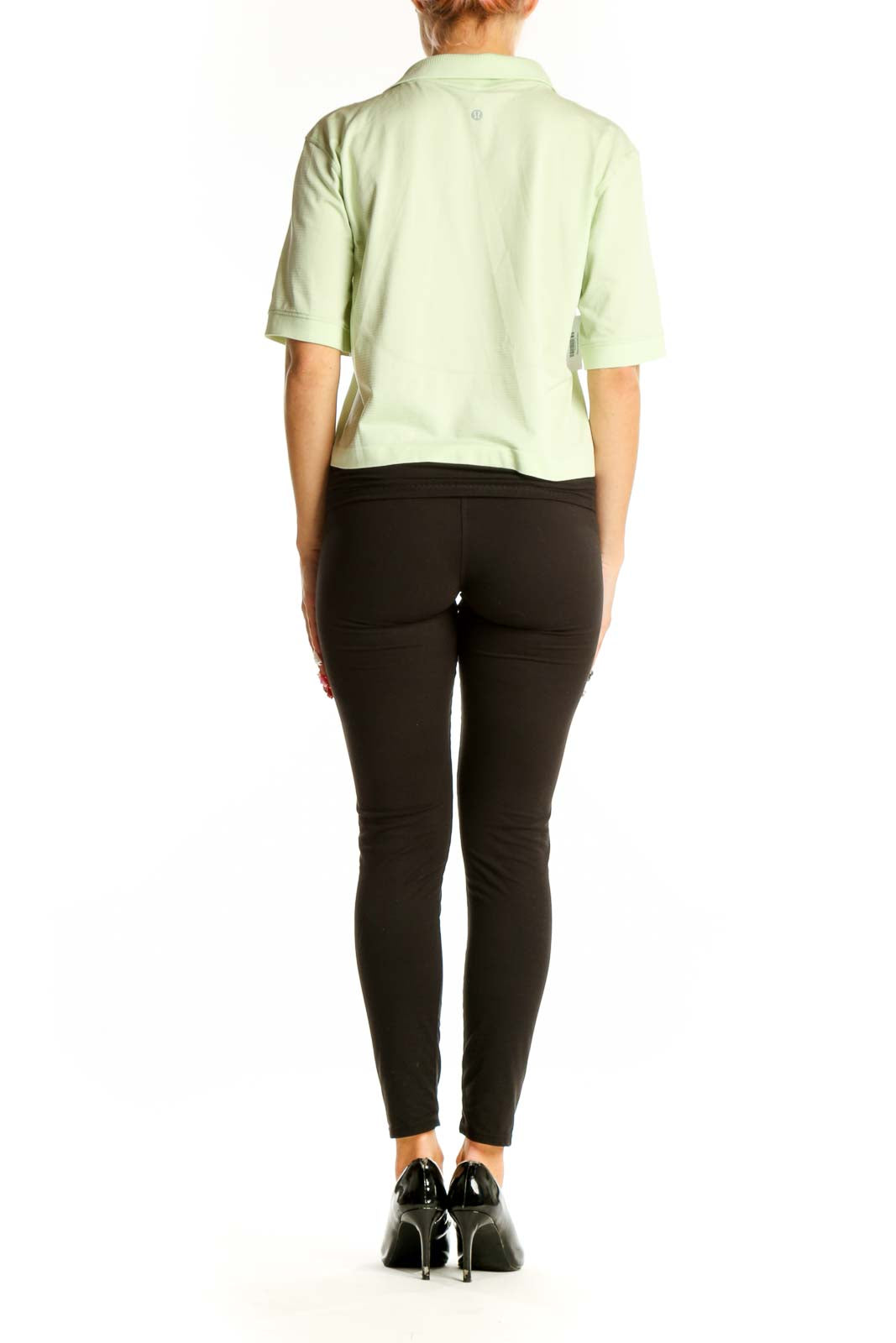 Side view of model wearing Lululemon mint green cropped polo top with black pants