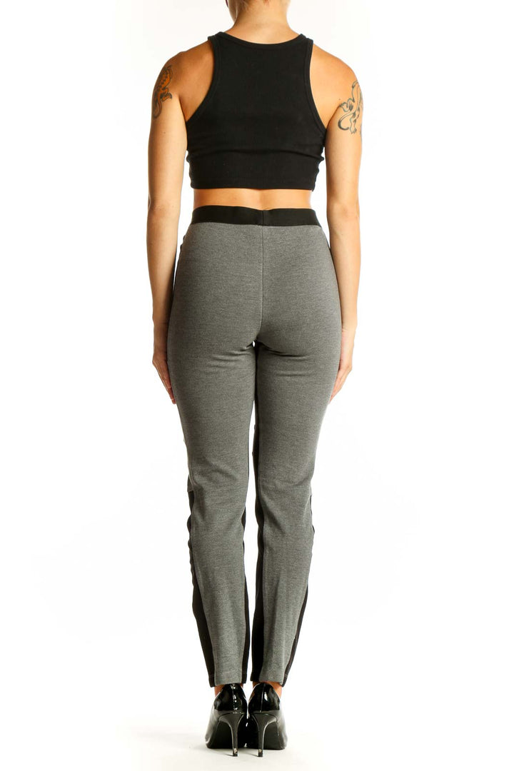 Side view of model wearing BCBG MaxAzria gray and black color block leggings with black crop top