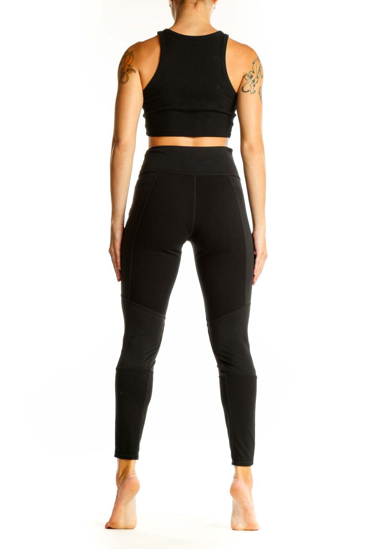 Side view of black Athleta leggings showing faux leather ankle details