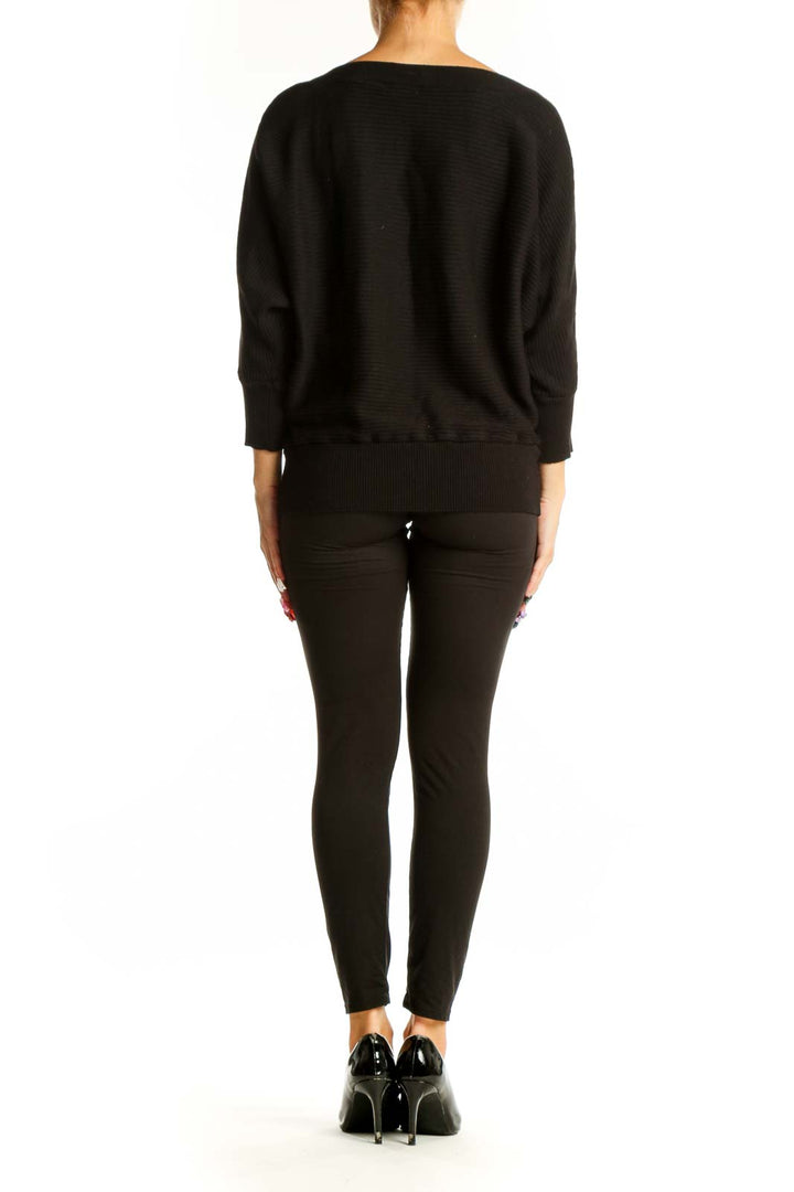 Side view of model wearing Dex black ribbed sweater with black pants