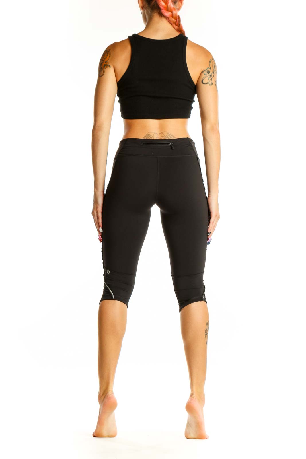 Side view of black Lululemon cropped athletic leggings with matching top on model