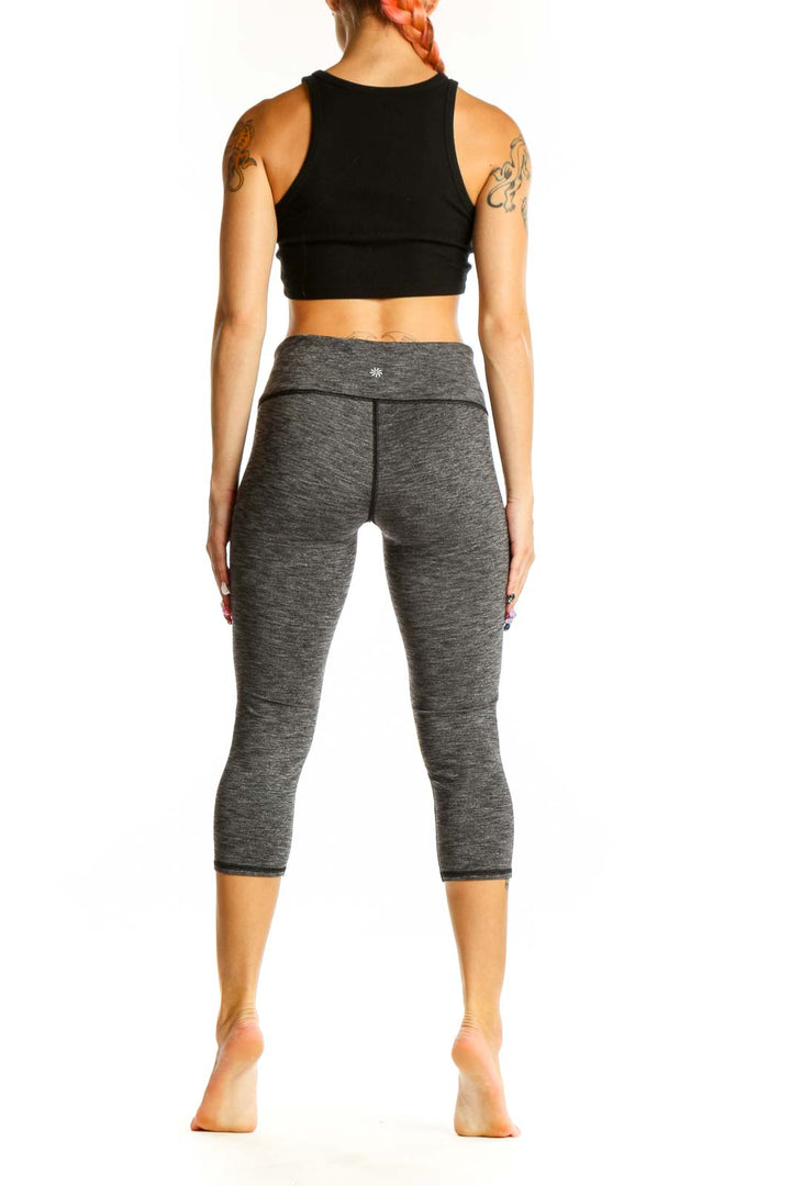 Side view of gray heathered Athleta capri leggings on model with black crop top